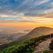 Panoramic view of lush green hills and rolling valleys in the Western Ghats near Bangalore under a clear blue sky.